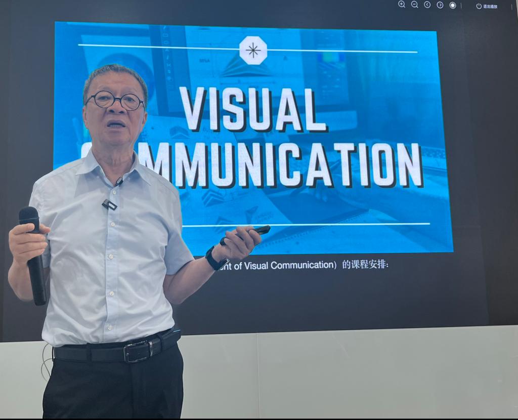 王受之在讲台前授课,屏幕上是 VISUAL COMMUNICATION