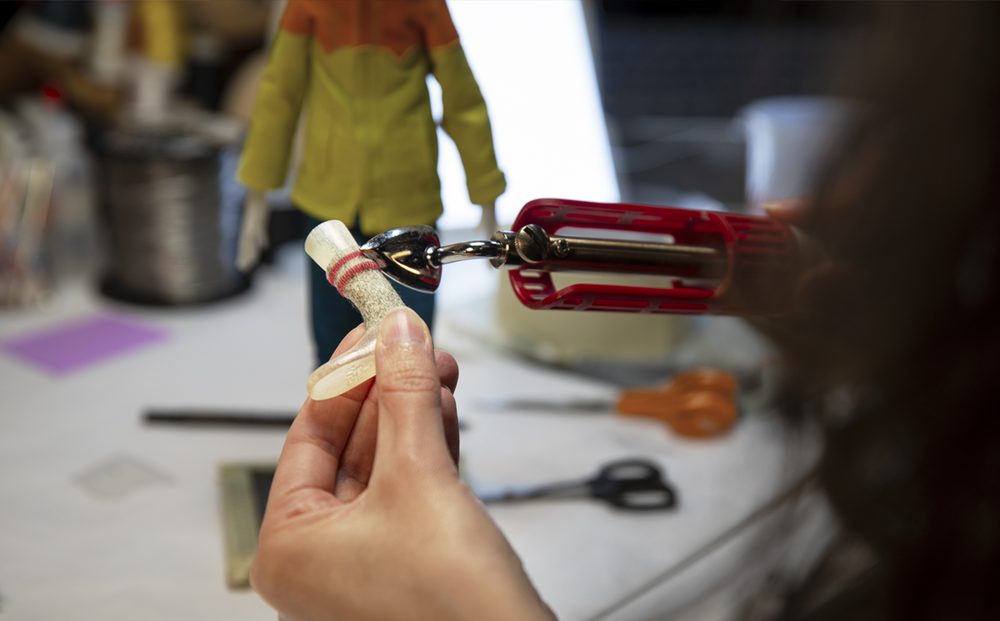LAIKA《Wildwood》展览制作现场：手持毛毡木偶的腿部部件，背景是待拍的木偶